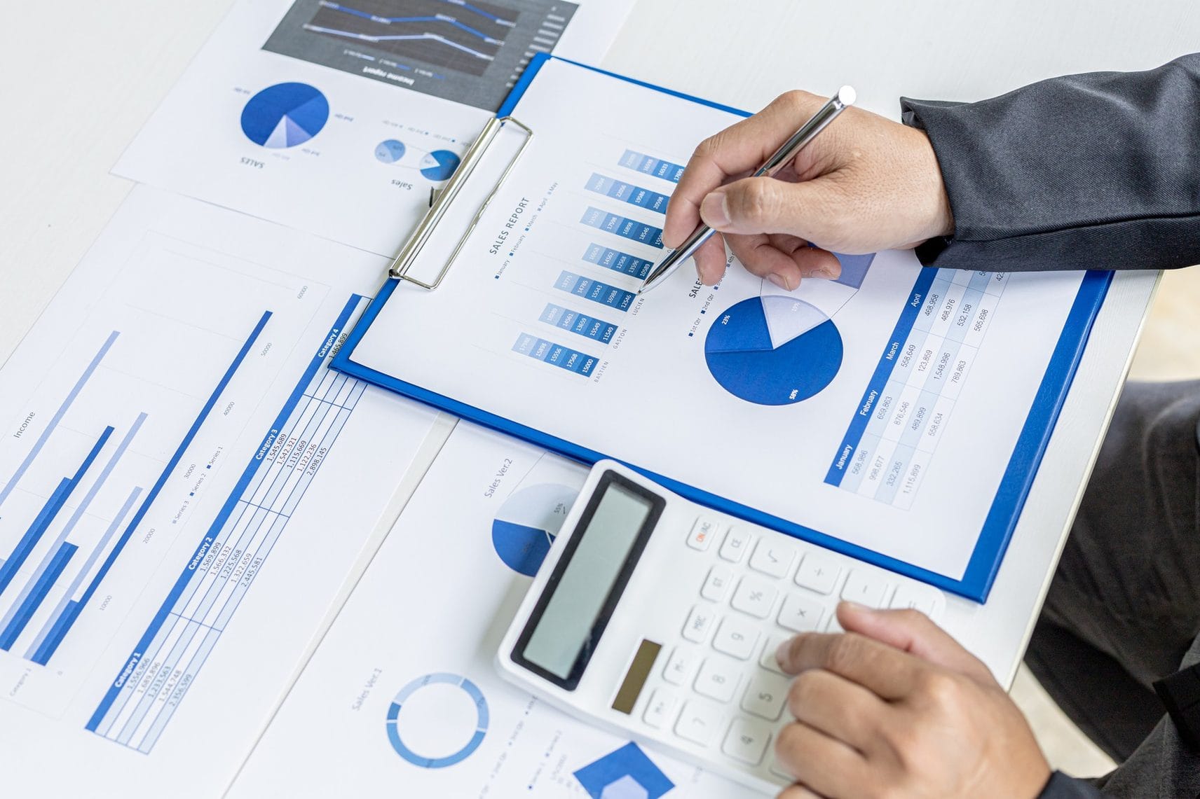 Bookkeeper reviewing charts and figures with a calculator